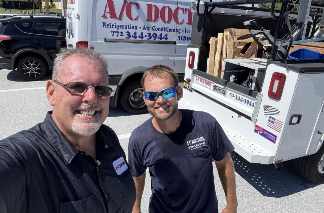 Two smiling men in front of an AC repair van.