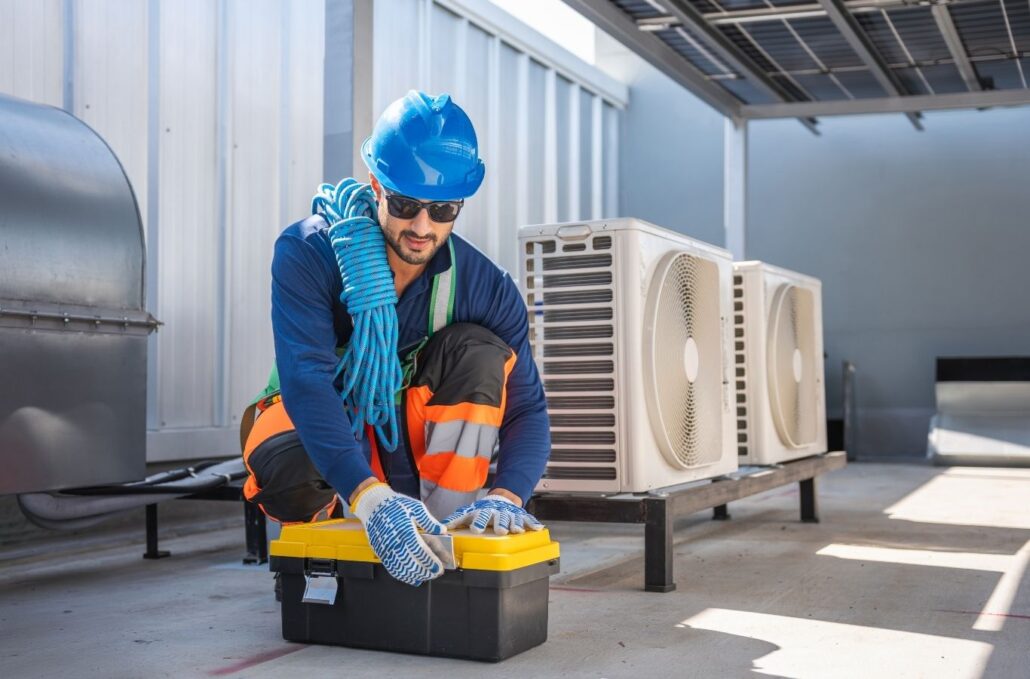 Experienced HVAC technician inspecting indoor air handler and testing cooling system performance