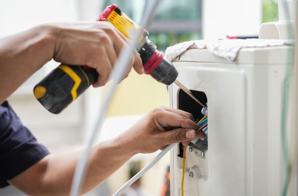 Experienced HVAC technician testing AC system performance with gauges and electrical tools
